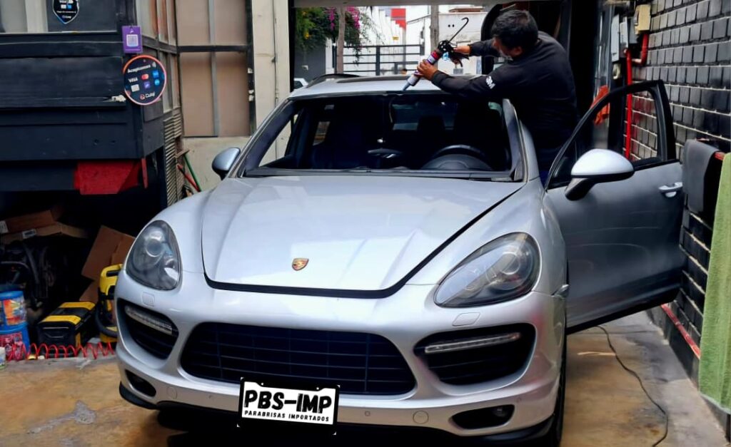 Técnico aplicando adhesivo para instalación de parabrisas en Porsche en Lima – taller en Surquillo